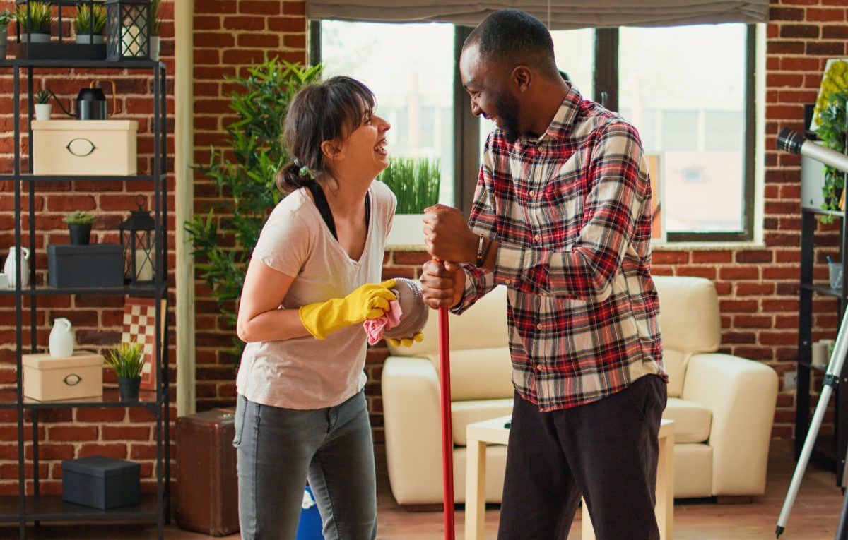 A couple smile at each other while spring cleaning