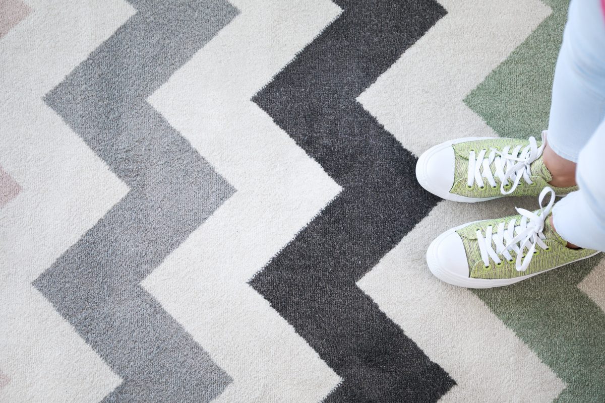 Top view of woman's sneakers standing on patterned clean carpet