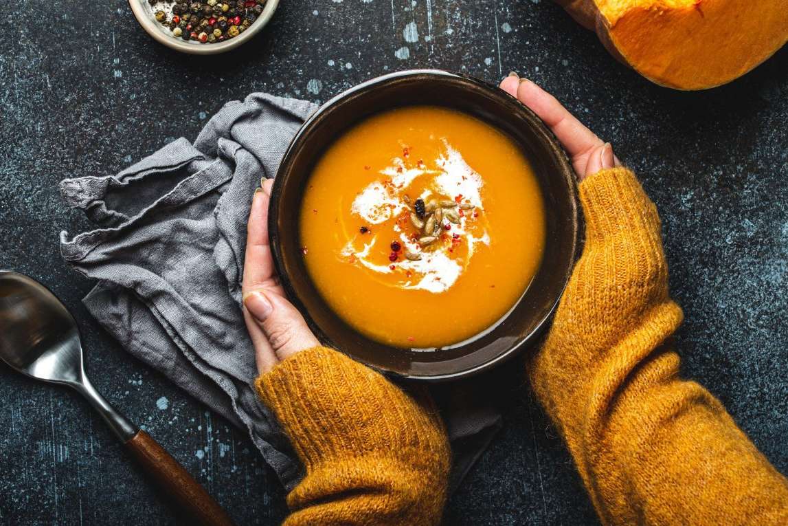 hands holding bowl of soup